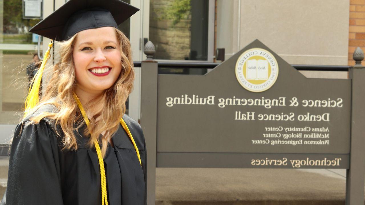 Lois Montgomery, Geneva graduate of 2019, 她戴着毕业帽，穿着毕业服，站在理工科大楼的标牌旁.